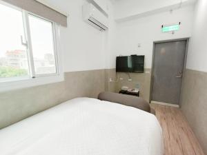 台南No 9 Hotel-九號文旅的卧室配有白色的床和电视