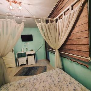 卡特佩BEYAZEV BUTİK OTEL MAŞUKİYE的一间卧室配有一张带窗帘的床和电视。