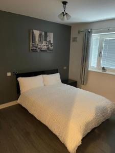 伍尔弗汉普顿Remarkable 2-Bed Apartment in Wolverhampton的卧室配有一张带白色棉被的床和窗户。