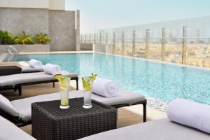 吉达Crowne Plaza - Jeddah Al Salam, an IHG Hotel的一个带躺椅和饮料的游泳池