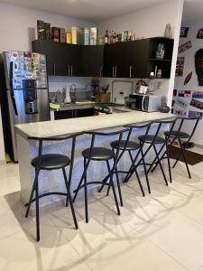 萨利纳斯Franches Apt, Amplio apartamento Familiar amoblado, San Lorenzo Salinas的厨房配有带凳子的柜台和冰箱。