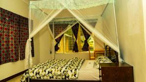 伊林加Pazuri House Iringa的一间卧室设有天蓬床和窗户。