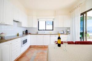 卡亚俄萨尔瓦赫Villa with Private Pool, Jacuzzi & 360° Sea Views的白色的厨房,桌子上放着两杯酒杯
