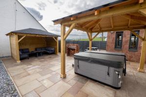 巴洛赫Westertonhill Lodge 8 Newbuild with Hot Tub Option的一个带烧烤架和凉亭的庭院