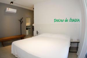 莫罗圣保罗Villa Amado的卧室配有白色床,墙上有标志
