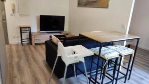 图卢兹Superbe appartement dans résidence avec piscine的客厅配有桌椅和电视。