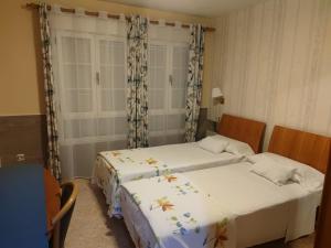 维拉弗兰卡·德尔·比尔Hostal Burbia的配有衬衫的小客房内的两张床