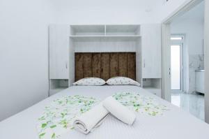 乌尔齐尼Flori Apartments的白色卧室配有一张大床和毛巾