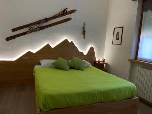 圣佩莱格里诺温泉BoTép ai Tigli的一间卧室配有一张绿色的床和木制床头板