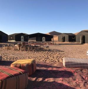 姆哈米德Chegaga desert Trips camp的沙漠中一组帐篷,配有桌椅