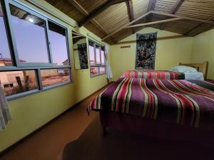 普诺Hanan Pacha Lodge的一间设有床铺的卧室,位于带窗户的房间内