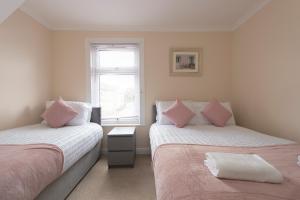 格雷斯瑟罗克Beautiful 2 bed house in Grays 4 separate beds sleeps 5的一间卧室配有两张带粉红色枕头的床和窗户。