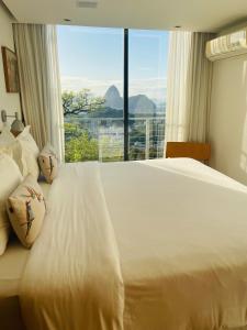 里约热内卢Pousada Rio144的卧室配有白色的床和大窗户