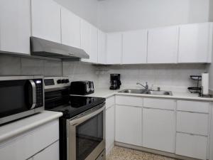 庞塞Cozy apartment in the heart of the city的厨房配有白色橱柜、炉灶和水槽。
