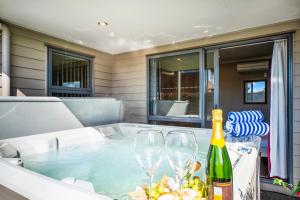 陶波The Grand @ Taupo的热水浴池,配有2杯酒和1瓶葡萄酒