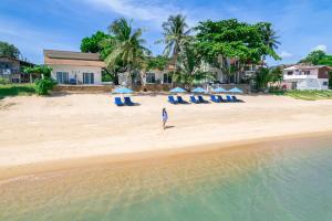 湄南海滩Baanfah Resort Samui的一位站在海滩上的妇女,她有椅子和遮阳伞