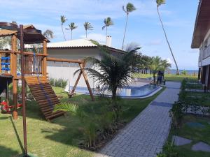 伊塔齐米林Itacimirim - Duplex Aconchegante, Pé na Areia的棕榈树屋前的游乐场