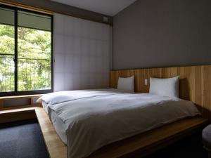 别府別府ホテル塒 Beppu Hotel Negura的一间卧室设有一张大床和一个大窗户