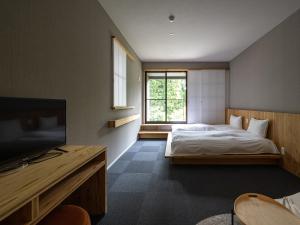别府別府ホテル塒 Beppu Hotel Negura的一间卧室配有一张床和一台电视