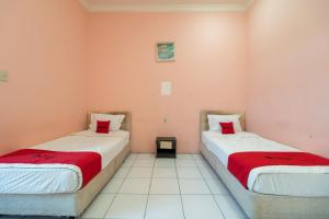 SiborongborongRedDoorz near Silangit International Airport的配有粉红色墙壁的客房内的两张床