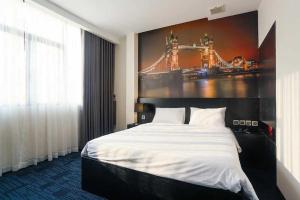 胡志明市DAISY HOTEL的卧室配有一张大床,墙上挂有绘画作品