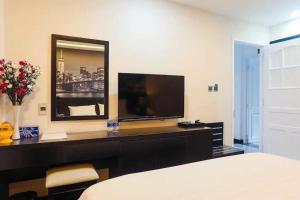 胡志明市DAISY HOTEL的一间卧室配有一张床、一台电视和一面镜子