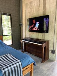 Ban Don MuangForest Guesthouse的一间卧室配有钢琴和平面电视