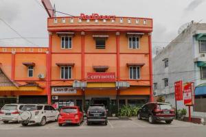 先达RedDoorz @ Pematangsiantar的一座橙色的建筑,汽车停在停车场