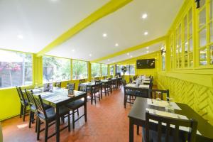 维耶尔宗Logis - Hotel Restaurant La Mire的餐厅设有桌椅和黄色的墙壁及窗户