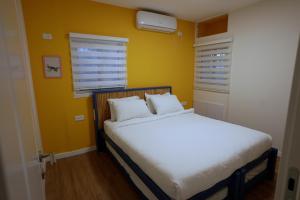 埃拉特RAKEFET - Traveler's House - EILAT的卧室配有白色床和黄色墙