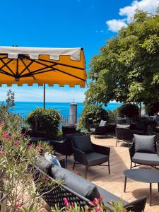 的里雅斯特马克西米利安里维埃拉酒店 的一个带椅子和遮阳伞的庭院和大海