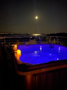 代森扎诺-德尔加达BELLAVISTA EXCLUSIVE B&B VISTA LAGO Piscina riscaldata e Jacuzzi的晚上在阳台上设有蓝色热水浴缸