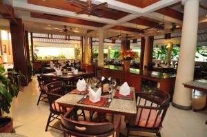 芭东海滩Phuket Leelavadee Hua Ting Resort的一间带桌椅的餐厅和一间酒吧