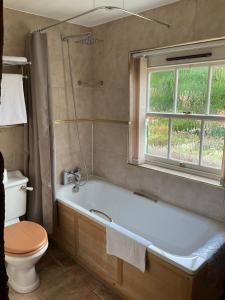 Bramley祖莉法玛宾馆的带浴缸、卫生间和窗户的浴室