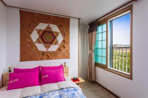 济州市济州和洋旅馆的一间卧室配有带粉红色枕头的床和窗户。