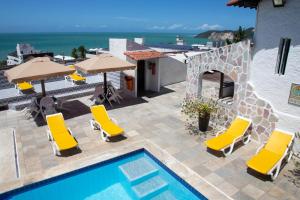 纳塔尔Santorini Praia Hotel的一座带椅子和遮阳伞的游泳池位于一座建筑旁边