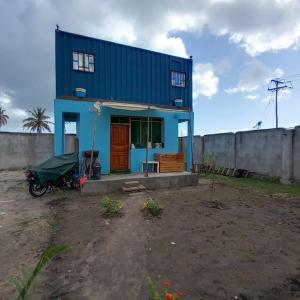 达累斯萨拉姆Beach House in Kigamboni Dar es Salaam的一辆停在前面的摩托车蓝色房子