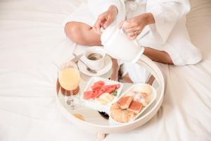 阿拉沙Grande Hotel Termas de Araxá的坐在床上的女人,带上一盘食物和牛奶