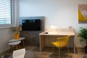 赫斯巴赫Livin63 Studio Apartments的客厅配有书桌和黄椅