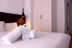 马德里马德里乌胡套房旅馆的一张带毛巾的床和一个标牌,上面写着醒醒房间