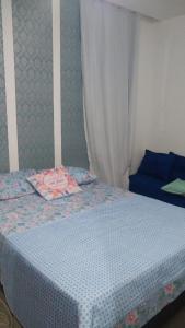 卡波布里奥Apartamento à beira mar Praia de Unamar的一间卧室配有一张带蓝色床罩和窗帘的床