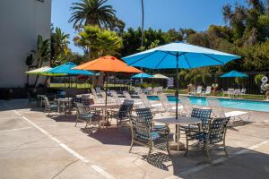 圣克莱门特圣克莱门特酒店的一组桌椅,在游泳池旁边配有遮阳伞