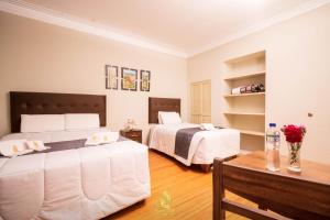 阿雷基帕Hostal Virreinal AQP的一间卧室配有两张床和一张鲜花桌