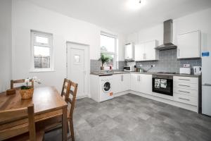 利Modern spacious 2 bedroom house in Leigh Self Service的厨房配有白色橱柜、桌子和炉灶。