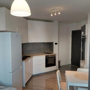 斯普利特Apartment Paola with free private parking place的厨房配有白色橱柜、桌子和白色冰箱。