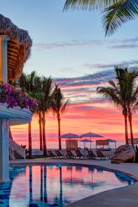 圣何塞德尔卡沃Mar del Cabo By Velas Resorts的棕榈树和日落的度假村游泳池