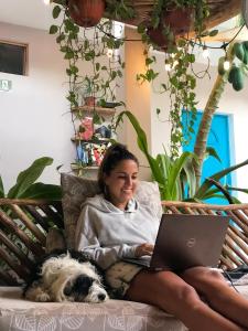奥尔沃克斯岛Barco Verde Hostel的坐在沙发上的女士,手提电脑和狗