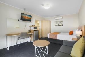 莱克斯恩特伦斯Comfort Inn & Suites Lakes Entrance的酒店客房配有一张床、一张书桌和一张沙发。
