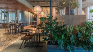 哥德堡Quality Hotel The Weaver的一间种有盆栽植物和桌椅的餐厅