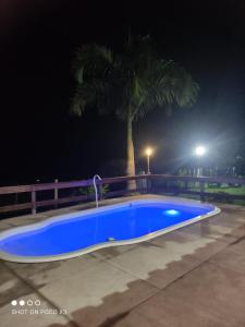 拉夫里尼亚斯Sítio Vista da Serra的蓝色的游泳池,晚上有棕榈树